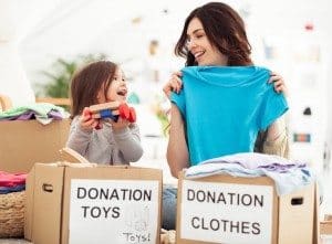 Mother and daughter preparing toys and clothes to donate for charity.
