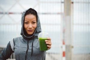 Successful urban sporty woman taking a rest for drinking nutritive detox smoothie. Fitness nutrition and healthy lifestyle concept.